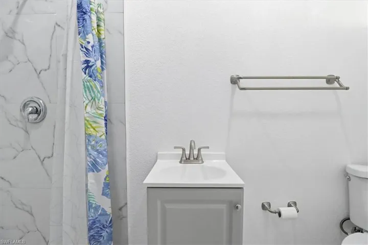 Bathroom featuring a marble finish shower, vanity, and a textured wall