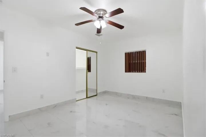 Unfurnished bedroom featuring a closet, ceiling fan, and light marble finish floors