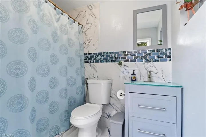 Full bathroom with vanity, a shower with shower curtain, and tile walls