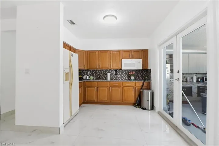 Kitchen with brown cabinetry, white appliances, and decorative backsplash