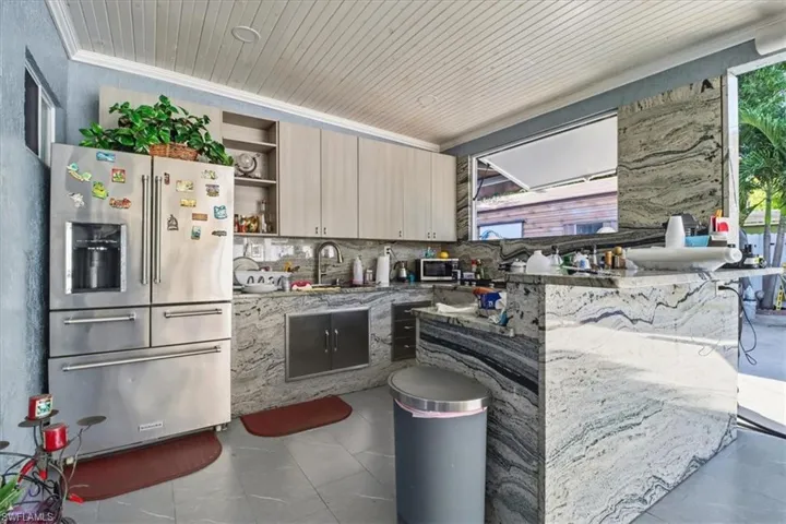 Kitchen with stainless steel appliances, open shelves, decorative backsplash, dark stone counters, and wooden ceiling