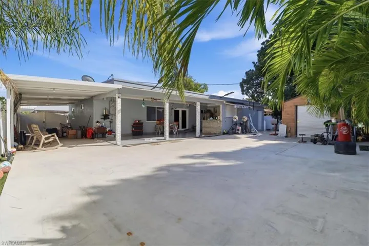 Rear view of property featuring a patio, an attached carport, and driveway