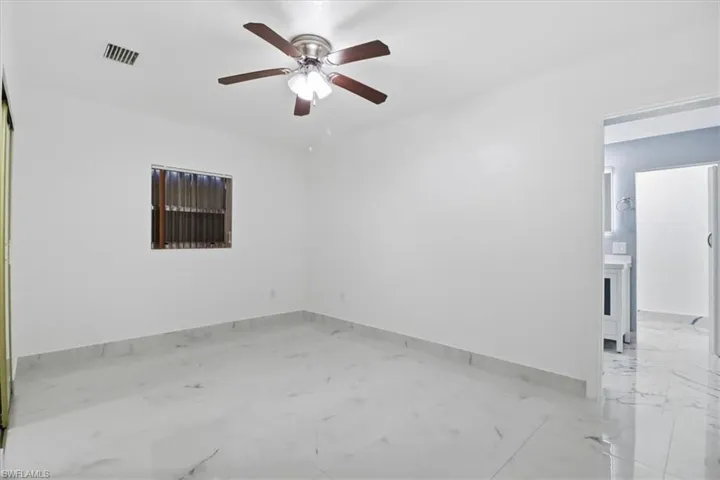 Unfurnished room featuring ceiling fan and light marble finish floors
