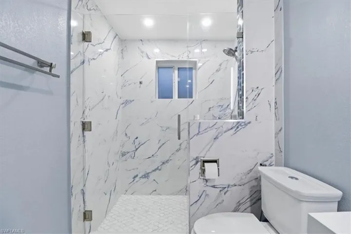 Bathroom with a marble finish shower, vanity, and a textured wall