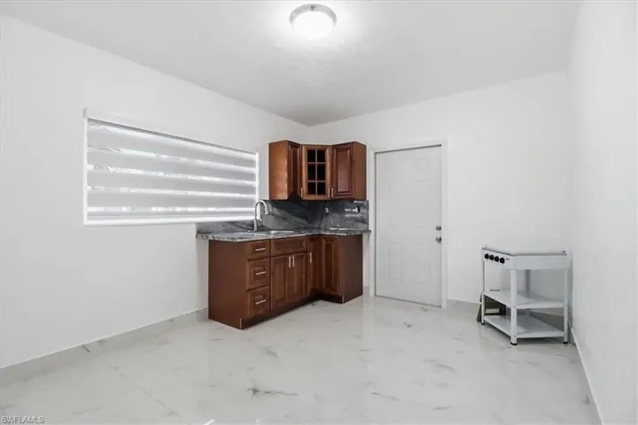 Kitchen featuring light marble finish flooring, glass insert cabinets, tasteful backsplash, and dark stone counters