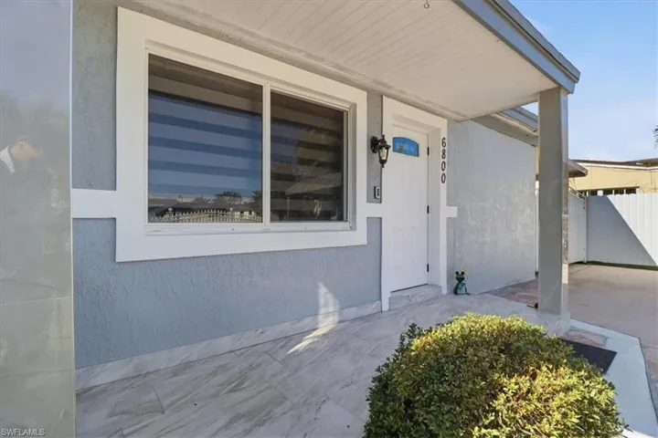 View of exterior entry featuring stucco siding and covered porch