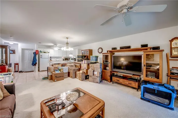Carpeted living room featuring ceiling fan with notable chandelier