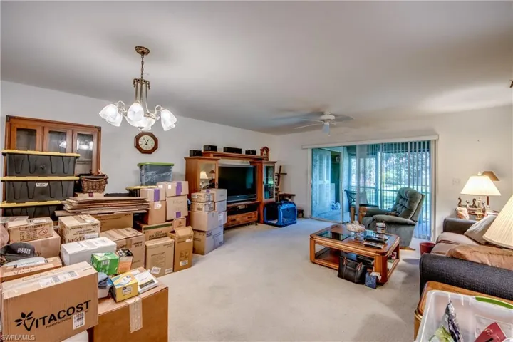 Carpeted living room with ceiling fan with notable chandelier