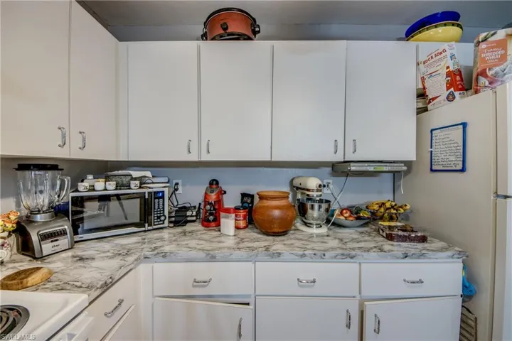 Kitchen with white cabinetry, light stone countertops, and stove