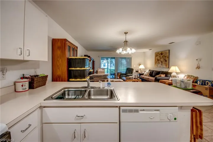 Kitchen featuring white cabinetry, white dishwasher, sink, and kitchen peninsula