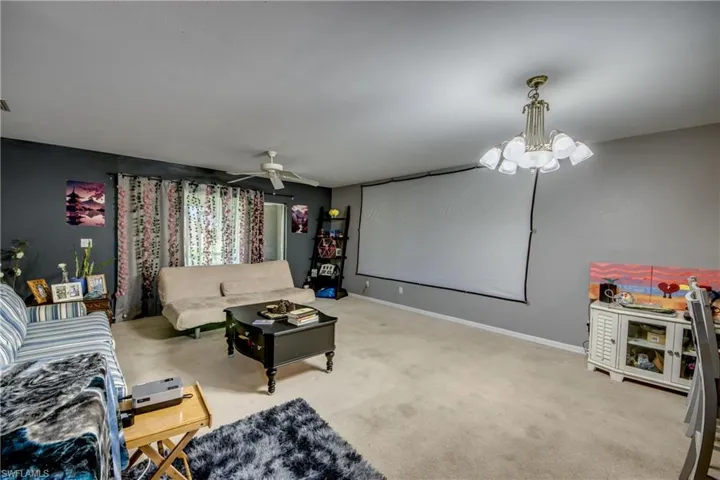 Carpeted living room featuring ceiling fan with notable chandelier