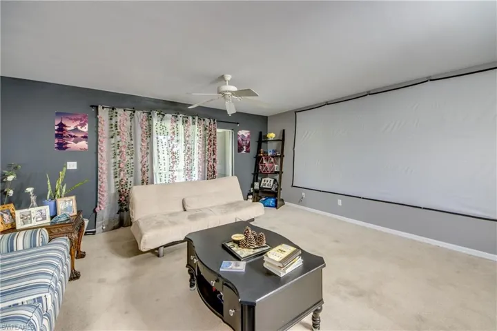 Carpeted home theater room featuring ceiling fan