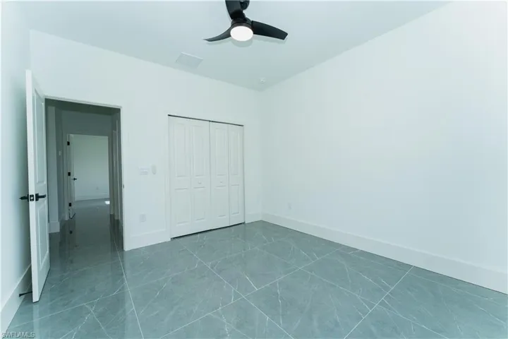 Unfurnished bedroom with a closet, baseboards, and a ceiling fan