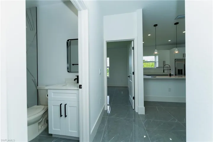 Bathroom with vanity, toilet, baseboards, and marble finish floors