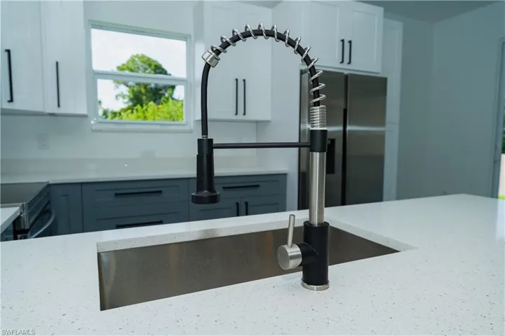 Kitchen with light stone countertops, white cabinets, and stainless steel range