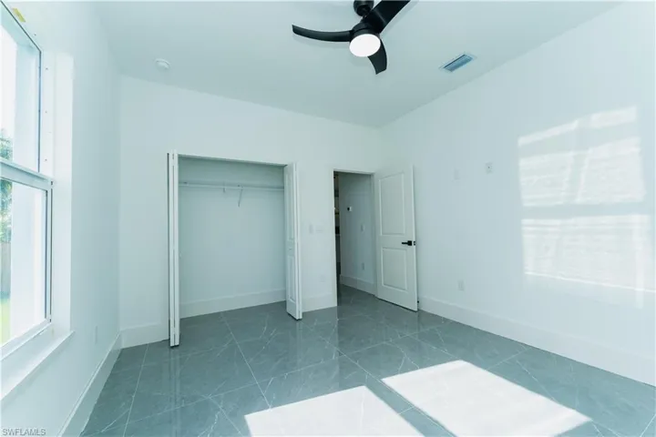Unfurnished bedroom with multiple windows, a closet, a ceiling fan, and baseboards