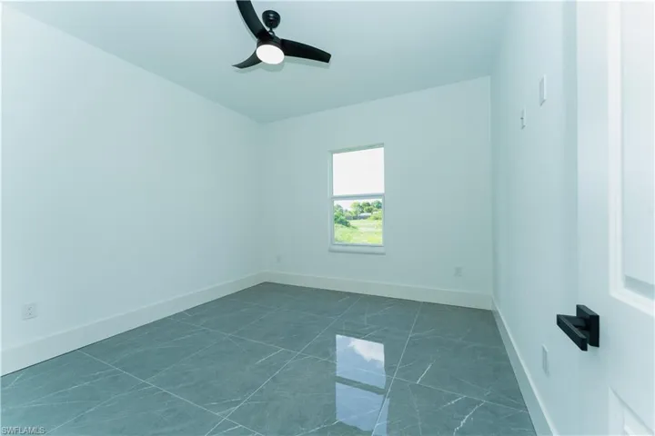Spare room with ceiling fan, baseboards, and dark marble finish flooring