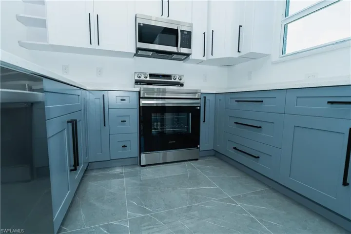Kitchen featuring stainless steel appliances, marble finish flooring, light countertops, and open shelves