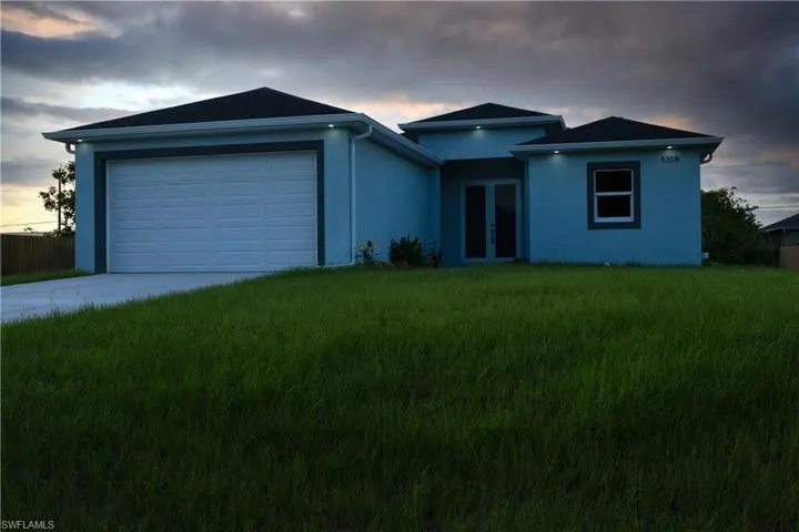 Single story home with french doors, driveway, a garage, a front lawn, and stucco siding