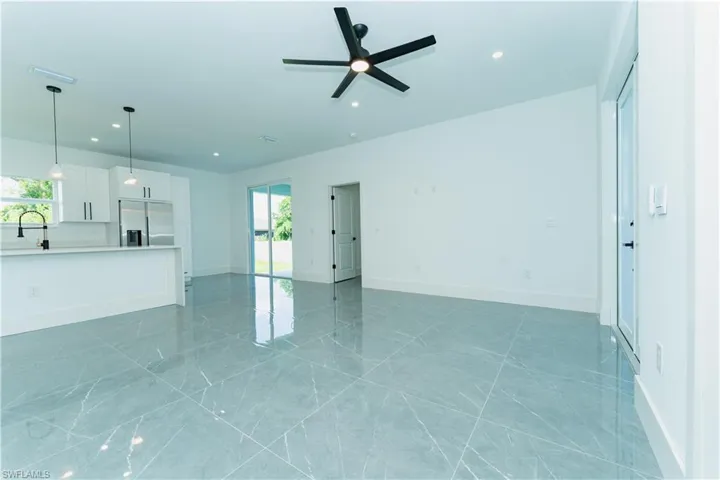 Unfurnished living room with a ceiling fan, recessed lighting, baseboards, a sink, and light marble finish flooring