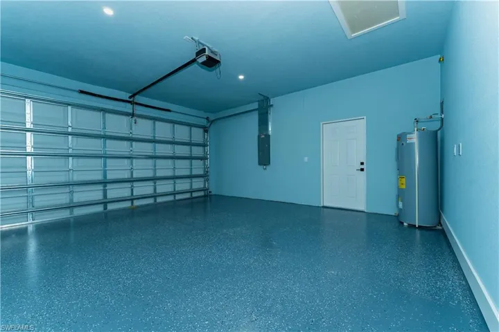 Garage with water heater, a garage door opener, and electric panel