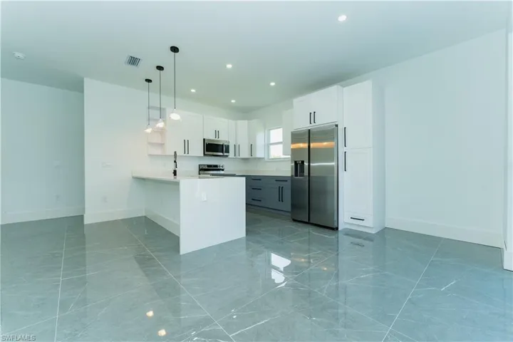 Kitchen with stainless steel appliances, a peninsula, light marble finish flooring, baseboards, and recessed lighting