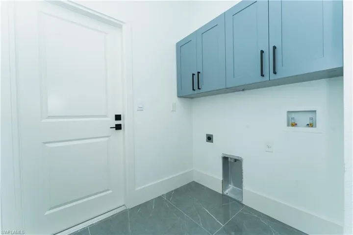 Laundry room featuring electric dryer hookup, cabinet space, washer hookup, baseboards, and dark marble finish flooring