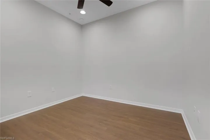 Empty room featuring dark wood-style floors, ceiling fan, and recessed lighting