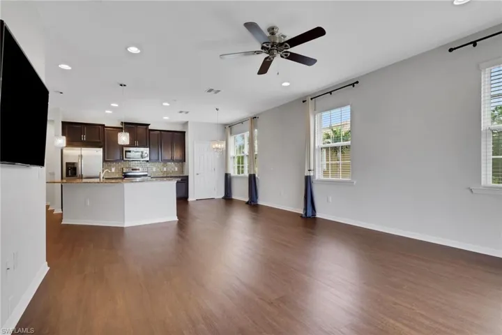 Unfurnished living room with recessed lighting, a ceiling fan, dark wood finished floors, and a chandelier