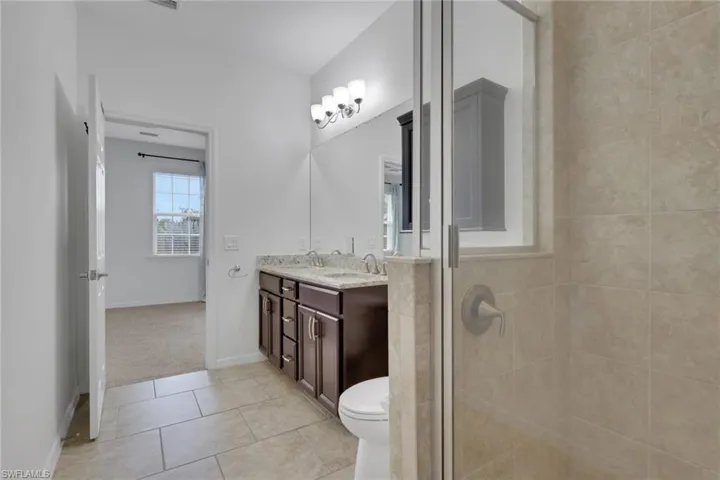 Bathroom with double vanity, light tile patterned floors, and a shower stall