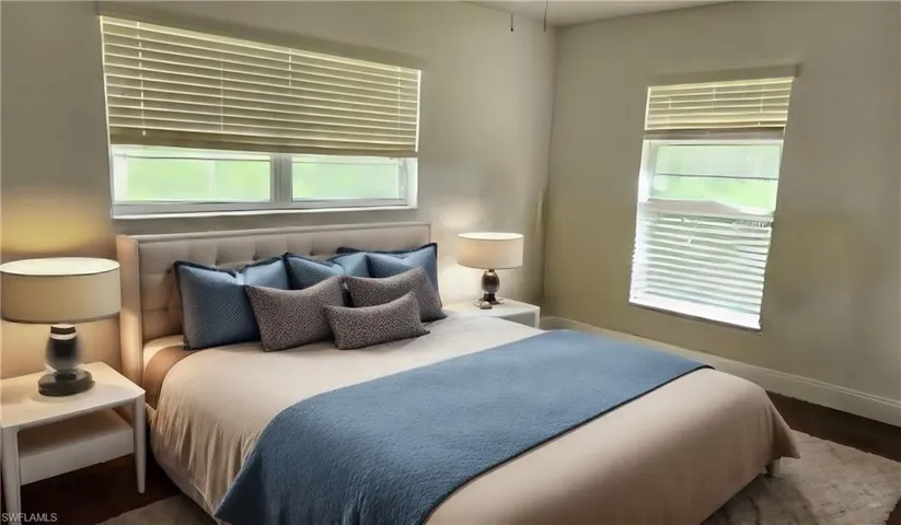 Bedroom featuring dark wood-type flooring and multiple windows