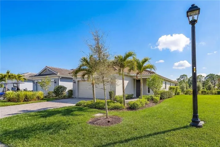 Ranch-style house featuring stucco siding, a front lawn, an attached garage, driveway, and a tiled roof