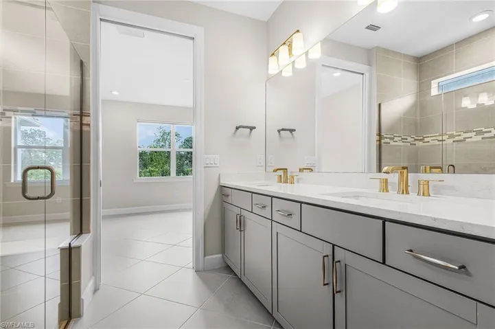 Bathroom featuring a stall shower, double vanity, light tile patterned floors, and recessed lighting