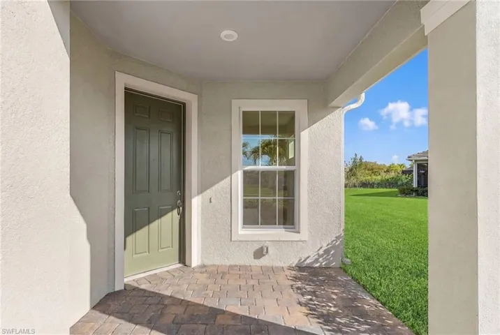 Doorway to property featuring a lawn, a patio area, and stucco siding