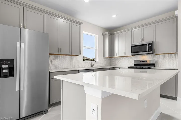 Kitchen featuring gray cabinets, stainless steel appliances, light tile patterned floors, a center island, and recessed lighting