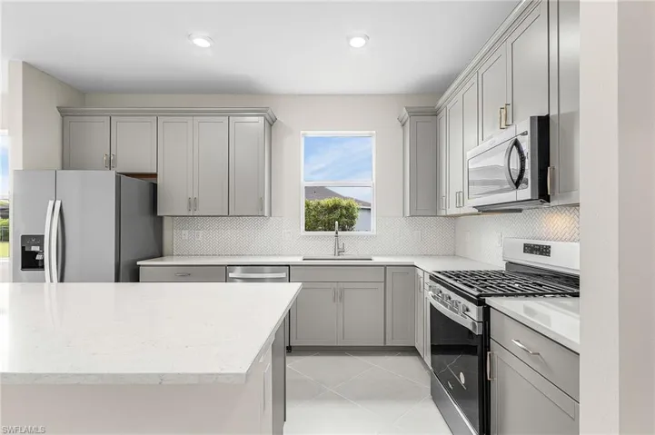Kitchen featuring gray cabinets, stainless steel appliances, light tile patterned flooring, and decorative backsplash