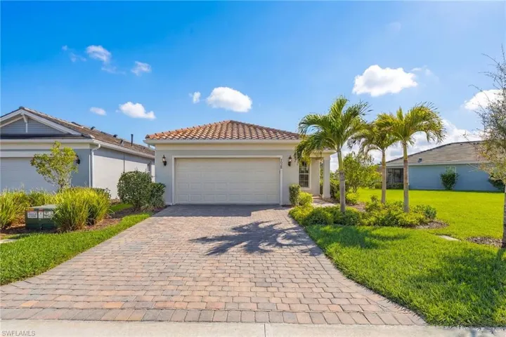 Mediterranean / spanish-style house with stucco siding, a garage, decorative driveway, a front lawn, and a tiled roof