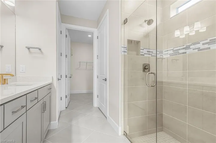Full bath featuring vanity, a stall shower, a walk in closet, and light tile patterned floors
