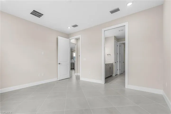 Unfurnished bedroom with ensuite bath and light tile patterned flooring