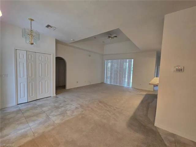 Unfurnished living room featuring light colored carpet and a chandelier