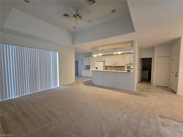 Unfurnished living room with light carpet and a raised ceiling