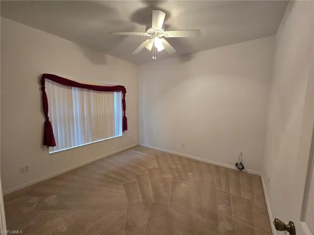 Carpeted spare room featuring ceiling fan