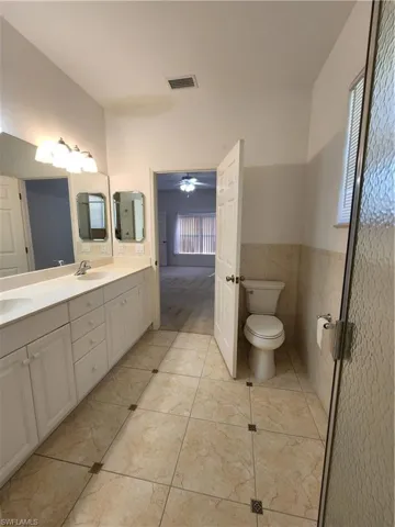 Bathroom featuring tile walls, tile patterned flooring, vanity, ceiling fan, and toilet