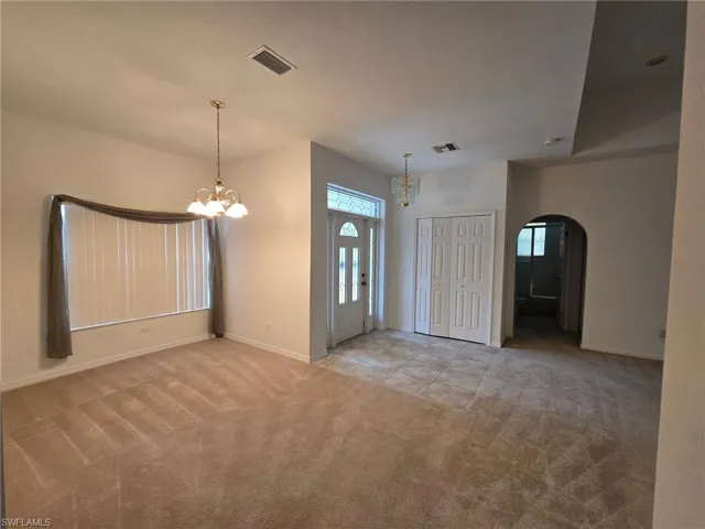 Entryway featuring an inviting chandelier and light colored carpet