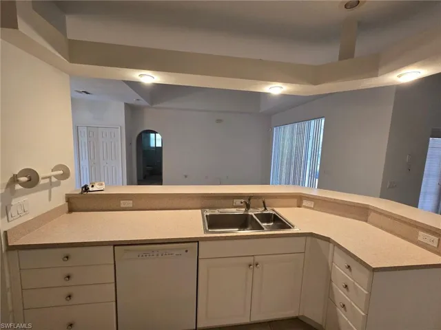 Kitchen with white dishwasher, sink, and white cabinets