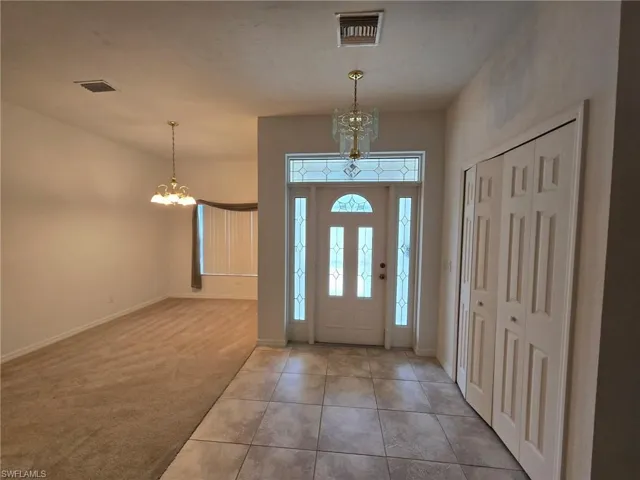 Carpeted entrance foyer with a notable chandelier