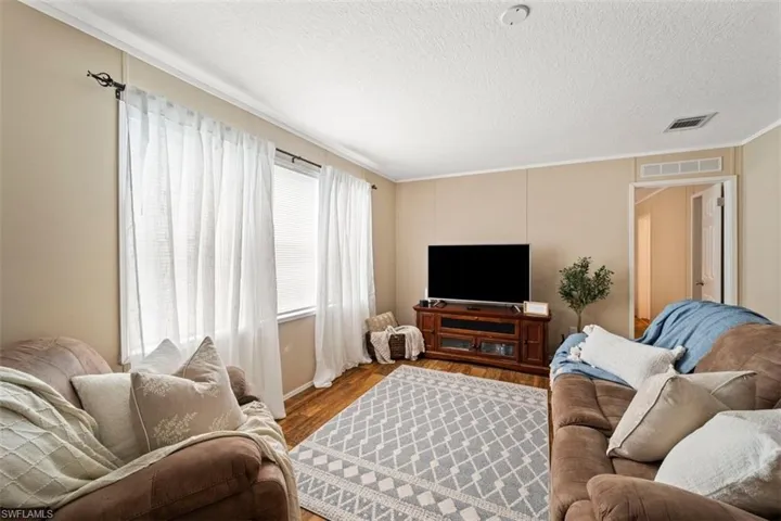Living room with crown molding, hardwood / wood-style flooring, and a textured ceiling