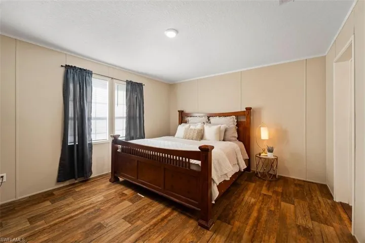 Bedroom with dark hardwood / wood-style floors, ornamental molding, and a textured ceiling