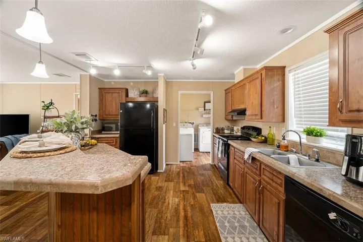 Kitchen with a textured ceiling, ornamental molding, black appliances, rail lighting, and sink
