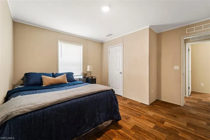 Bedroom with crown molding and dark wood-type flooring